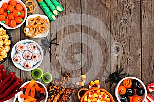 Halloween candy buffet table corner border over a rustic wood background with copy space