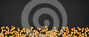 Halloween candy corn bottom border banner on a black background with copy space