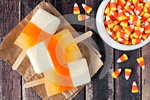 Halloween candy corn popsicles on rustic wood background