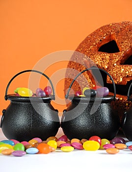 Halloween candy in trick or treat carry cauldrons with pumpkin - vertical closeup.