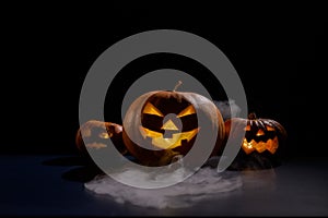 Halloween card. jack o lantern with candles glow on a black background. A row of creepy pumpkins with carved grimaces