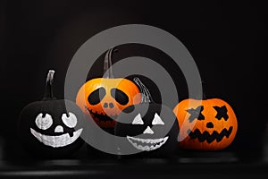 Halloween celebration. Pumpkins with drawn faces on table in darkness