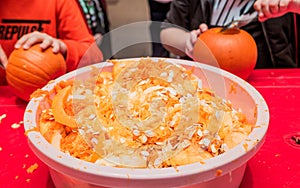 Halloween celebration in the shopping center. Children are carving a figure out of a pumpkin,