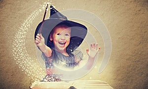 Halloween. cheerful little witch with a magic wand and glowing b