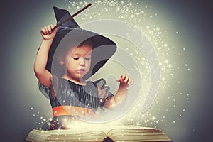 Halloween. cheerful little witch with a magic wand and glowing b