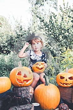 Halloween. Child dressed in black with jack-o-lantern in hand, trick or treat. Little girl pumpkin in the wood, outdoors. Toned p