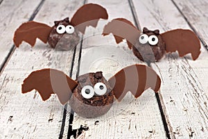 Halloween chocolate donut hole bats against white wood
