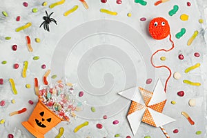 Halloween composition with orange candy bucket, jujubes, spider