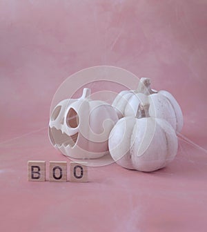 Halloween Composition with White Scary Pumpkins and Cobweb on a Pastel Pink Grunge Background.