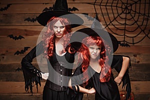 Halloween Concept - Beautiful caucasian mother and her daughter with long red hair in witch costumes with angry fussy