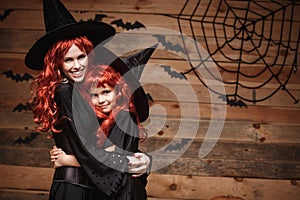 Halloween Concept - Beautiful caucasian mother and her daughter with long red hair in witch costumes happy smiling and