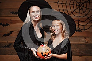 Halloween Concept - beautiful caucasian mother and her daughter in witch costumes celebrating Halloween with sharing Halloween can