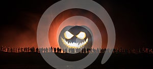 Halloween concept. Blurred silhouette of giant Jack-o-lantern pumpkin with scary smiling face behind crowd at night. People looks