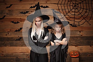 Halloween Concept - cheerful mother and her daughter in witch costumes disappointing with something.