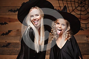 Halloween Concept - Closeup beautiful caucasian mother and her daughter in witch costumes celebrating Halloween posing with curved