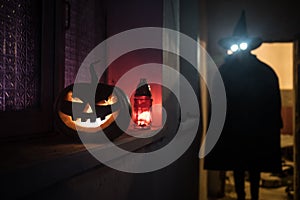 Halloween concept. Creepy silhouette in the dark corridor with pumpkin head. Toned light with fog on background