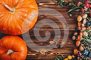 Halloween concept with fresh pumpkins and flowers with spiders on the wooden table. Trick or Treat view from above