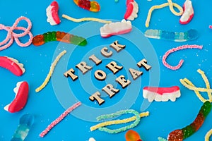 Halloween concept. Halloween party decorations with words TRICK OR TREAT, sweets, top view flat lay on blue background