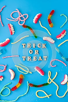 Halloween concept. Halloween party decorations with words TRICK OR TREAT, sweets, top view flat lay on blue background