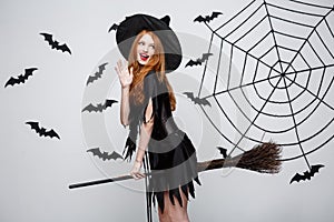Halloween Concept - Happy elegant witch enjoy playing with broomstick halloween party over grey background.