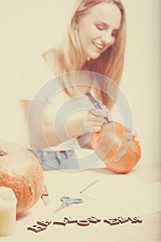 Halloween concept, happy Girl sitting at table with pumpkins preparing for holiday with candle and rope, drawing how to do Jack