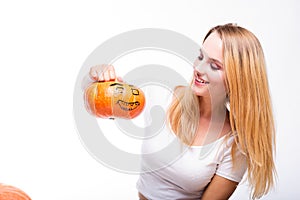 Halloween concept, happy Girl sitting at table with pumpkins preparing for holiday with candle and rope, holding Jack