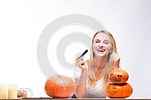 Halloween concept, happy Girl sitting at table with pumpkins preparing for holiday with candle and rope, Jack lantern, funny and