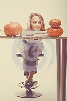 Halloween concept, happy Girl sitting at table with pumpkins preparing for holiday with candle and rope, Jack lantern, funny and