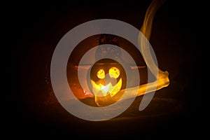 Halloween concept. Jack-o-lantern smile and scary eyes for party night. Close up view of scary pumpkin with witch hat on at dark f
