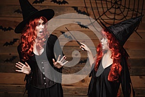 Halloween Concept - little red hair witch using magic with magic wand to her mother with shocked expression.