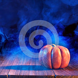 Halloween concept - Orange pumpkin lantern on a dark wooden table with double colored smoke around the background, trick or treat