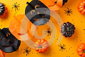 Halloween concept. Top view photo of jack-o-lantern shaped garland pumpkins spiders and black confetti on isolated orange