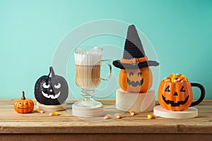 Halloween creative concept with latte macchiato coffee cup, candy corn and jack o lantern pumpkin decor on wooden table
