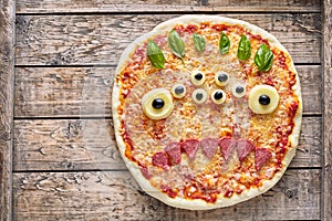 Halloween creative scary food monster zombie face with eyes pizza snack mozzarella, basil and sausage