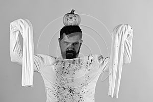 Halloween, culture and traditions concept. Guy with beard holds pumpkin