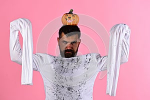 Halloween, culture and traditions concept. Guy with beard holds pumpkin