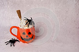 Halloween cup of coffee orange pumpkin cup with spiders on gray background, copy space