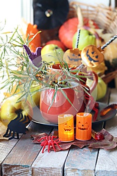 Halloween decor, a couple of cups with a drink, decorative candles, pumpkins, berries, leaves on the windowsill