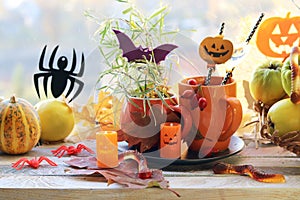 Halloween decor, a couple of cups with a drink, decorative candles, pumpkins, berries, leaves on the windowsill