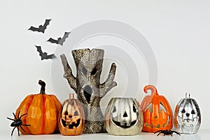 Halloween decor with jack o lantern and spooky tree against a white wall