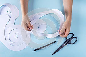 Halloween decorarion. Concept DIY and children creativity. Step-by-step instructions: making ghosts from paper. Step 2 child cut photo