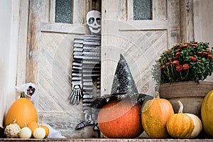 Halloween decorated front door with various size and shape pumpkins and skeletons. Front Porch decorated for Halloween.