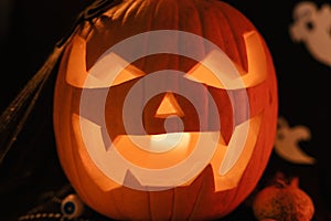 Halloween Decoratins on Table. Halloween Pumpkin. Traditional Treats. Big Scared Pumpkin Close Up. Glowing Pumpkin photo