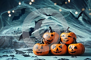 Halloween decoration with funny pumpkin heads, spider, web and flying bat on mystical bokeh background.