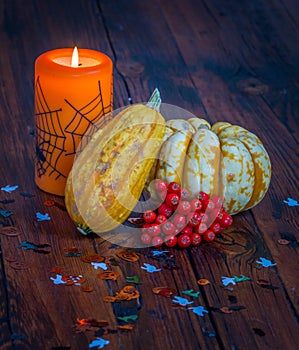 Halloween decorations, lit candle and pumpkins on a wooden table