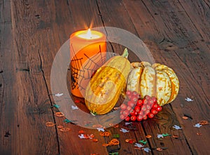 Halloween decorations, lit candle and pumpkins on a wooden table