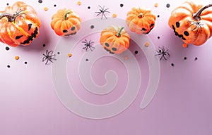Halloween decorations made from pumpkin, paper bats, black spider on pastel background