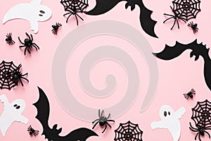 Halloween decorations on pastel pink background. Happy Halloween concept. Flat lay composition with ghosts, spiders, webs, bats