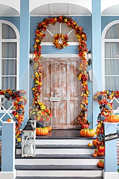 Halloween design home with yellow fall leaves and lanterns. House entrance staircase decorated for autumn holidays, fall flowers