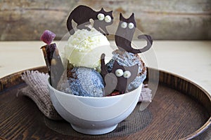 Halloween dessert in a white cup. It consists of ice cream and chocolate black cats.